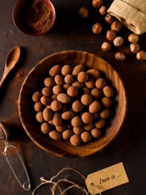 Chocolates in a wooden bowl on dark rustic background